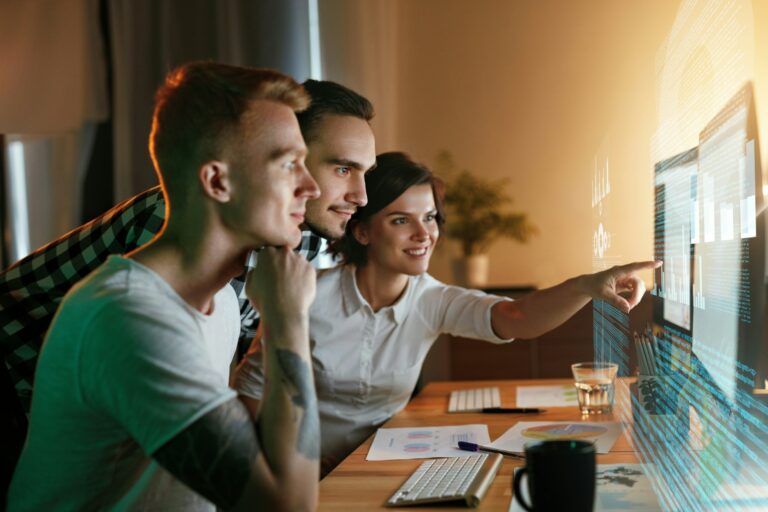 AI literacy in the workplace and why it is the business advantage a group of employees at a computer with a futuristic screen depicting an AI literate team